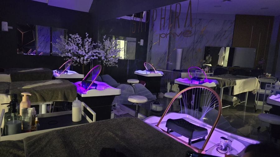 Cabina de lavado del Spa Capilar con puestos iluminados, arcos de cobre y el rótulo Sapphira Privé