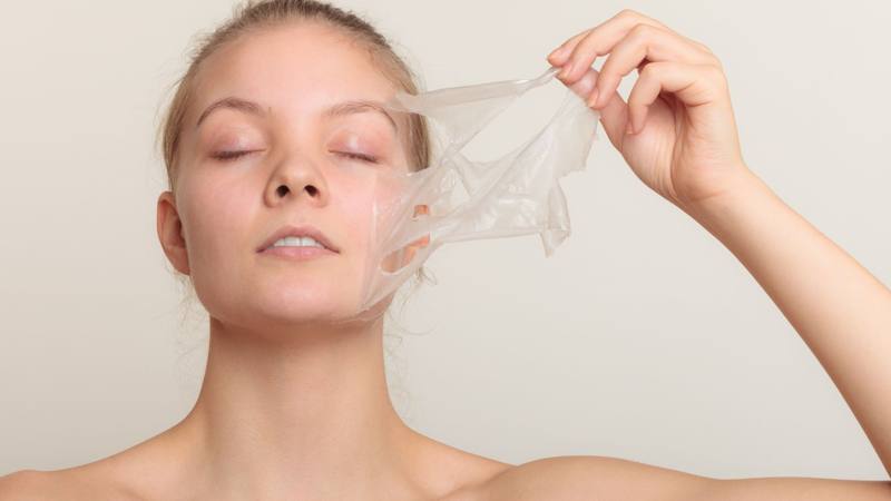 Mujer retirando una mascarilla facial transparente