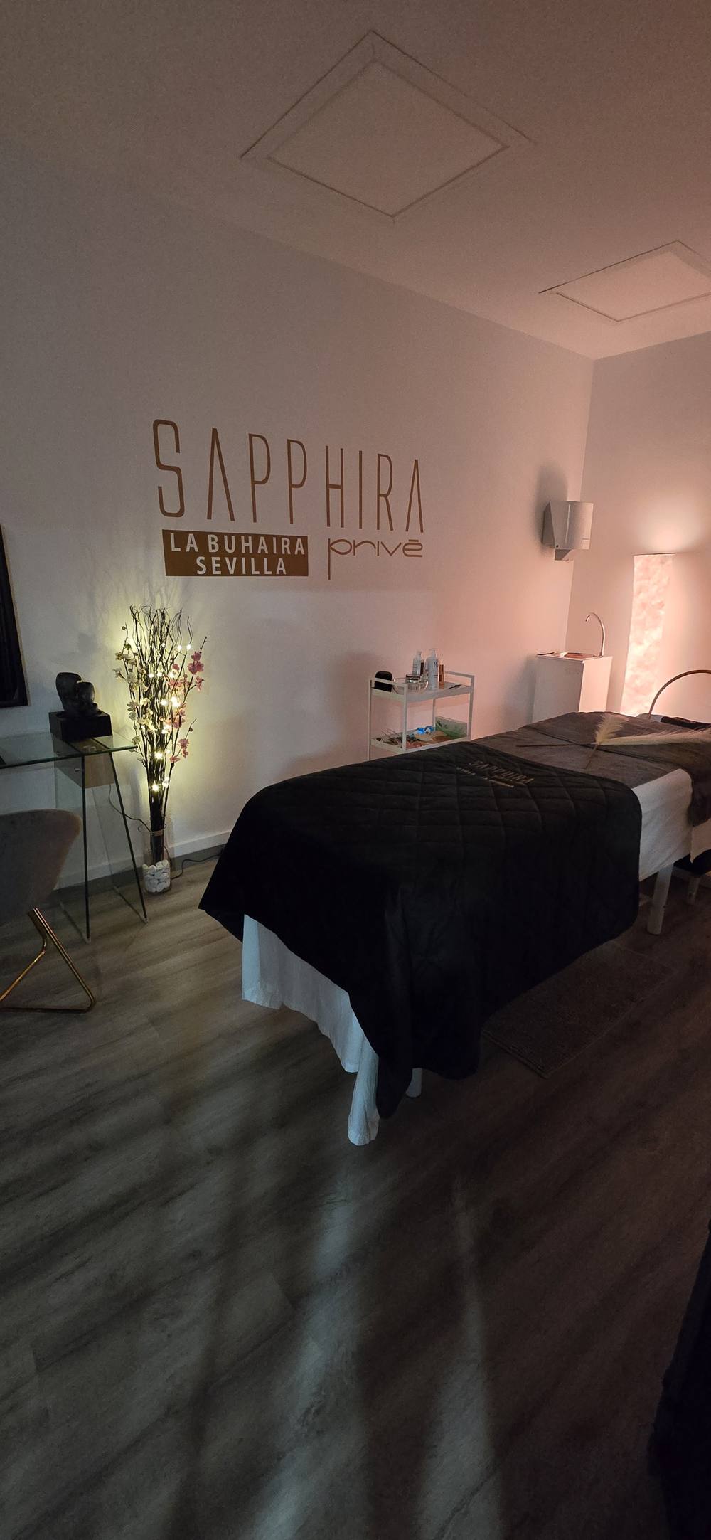 Sala individual de spa capilar con camilla y ramas iluminadas